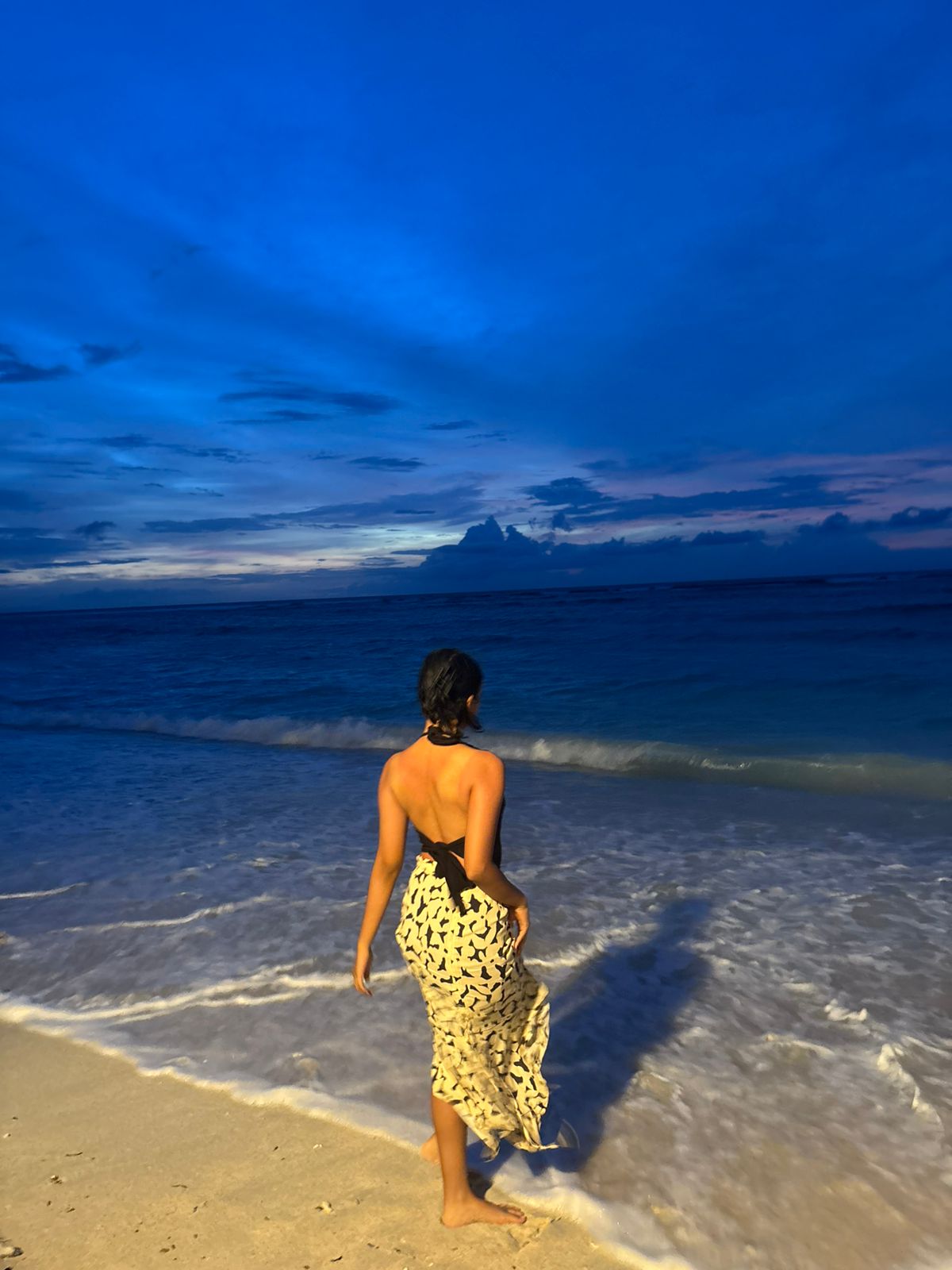Woman walking toward the sea at dusk